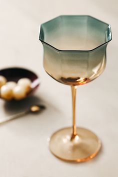 an empty glass sitting on top of a table next to a bowl and spoons