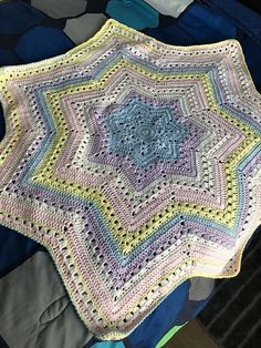 a crocheted blanket sitting on top of a bed next to a blue pillow