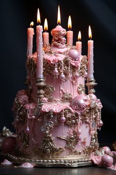 a pink and gold cake with lit candles