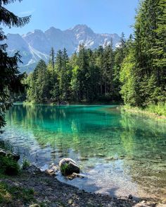 a lake surrounded by trees and mountains in the background