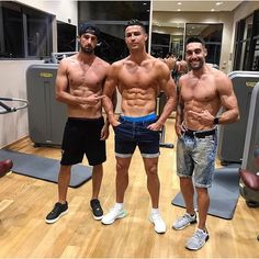 two men standing in front of a gym machine posing for the camera with their shirts off