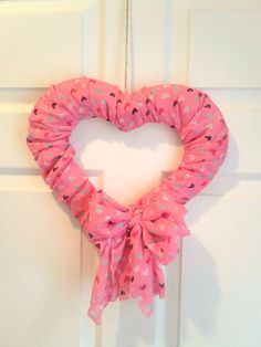 a heart shaped wreath hanging on the front door with pink and blue polka dot fabric