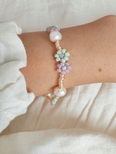 a close up of a person wearing a bracelet with pearls and beads on it's arm