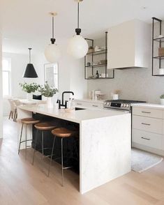 a kitchen island with stools and lights hanging from it's ceiling over the counter