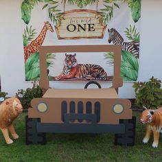 two fake animals are standing next to a cardboard jeep with a tiger and giraffe on it