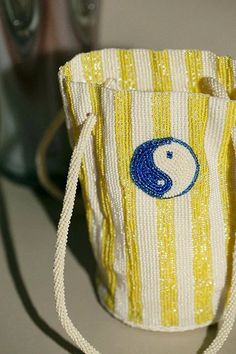 a yellow and white striped bag with a blue yin symbol on the front, sitting next to two soda cans