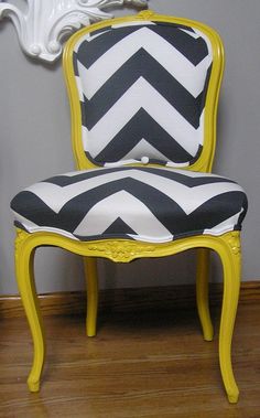 a yellow chair with black and white chevroned upholstered seat sits in front of a gray wall