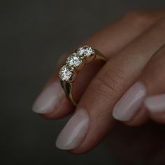 a woman's hand holding a three stone diamond ring