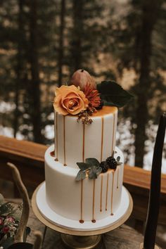 a three tiered cake sitting on top of a wooden table next to a forest