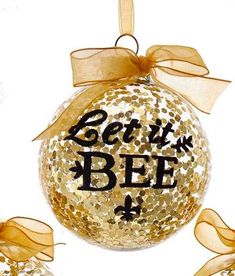 a glass ornament with the words bert and bee on it, hanging from a ribbon