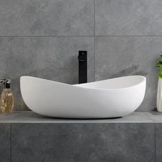 a white bowl sink sitting on top of a counter next to a vase with flowers