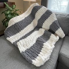 a gray and white blanket sitting on top of a couch