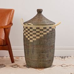 a brown leather chair sitting next to a large woven basket on the floor in front of a white wall