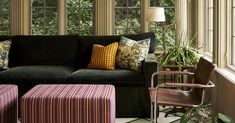 a living room filled with lots of furniture next to a window covered in plants and trees