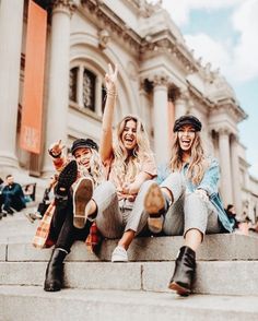 two women sitting on steps with their feet up in the air and one woman raising her hand