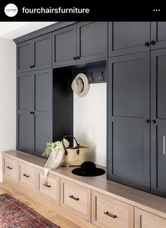 an entryway with gray cabinets and hats on it's shelf, next to a rug