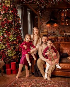 a family sitting on a couch in front of a christmas tree