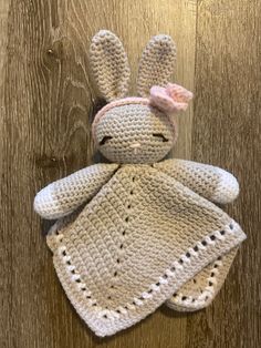 a crocheted stuffed animal with a pink bow on its head sitting on a wooden surface