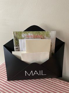 a mailbox with an envelope in it sitting on a striped table cloth next to a white wall