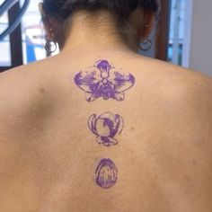 the back of a woman's neck with three orchids on it