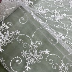 two white laces are laying on top of a green cloth with flowers and leaves