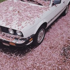 an old white car covered in pink flowers