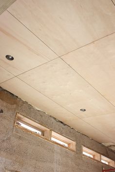 an unfinished ceiling with three windows in it