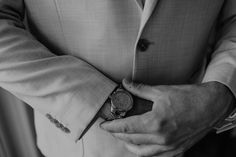 a man in a suit and tie is holding his hand on his pocket while wearing a watch