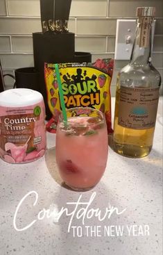 a pink drink sitting on top of a counter next to bottles of liquor and other items