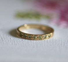 a close up of a gold ring on a white surface with flowers in the background