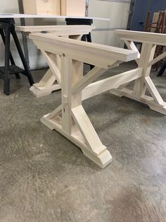 a wooden bench sitting on top of a floor next to a table with two chairs behind it