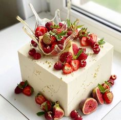 a square cake with strawberries and raspberries on top is sitting in front of a window