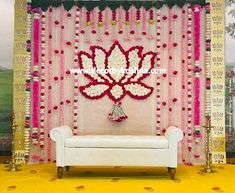 a white couch sitting in front of a wall decorated with flowers and beads on it