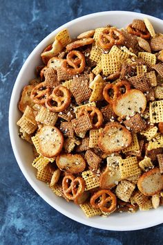 a bowl filled with cheetos and pretzels on top of a blue table