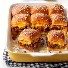 several cheeseburger sliders in a yellow casserole dish on a black and white checkered cloth