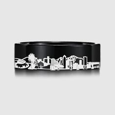 a black and white cityscape ring with palm trees on the inside, in front of a gray background