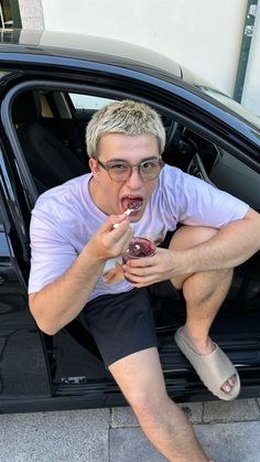 a man sitting in the back of a car eating a donut with his mouth open