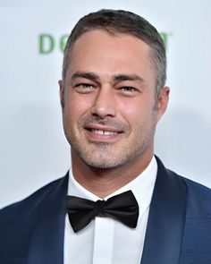 a man in a tuxedo and bow tie smiling for the camera at an event