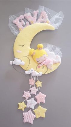 a baby mobile with a sleeping girl on the moon and stars hanging from it's side