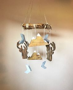 a wind chime hanging from the ceiling with mountains and trees on it's sides