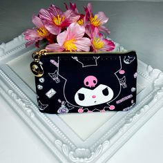 a black purse with pink and yellow flowers in it sitting on a white tray next to a mirror