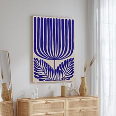 a blue and white artwork hangs on the wall next to a dresser with two vases