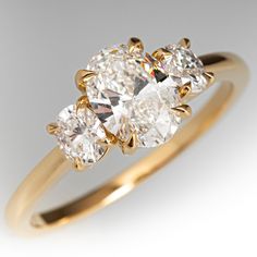 three stone diamond ring with yellow gold setting on white background, close up view from the side