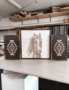 three framed art pieces sitting on top of a counter