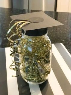 a graduation cap sits on top of a jar filled with gold confetti and streamers