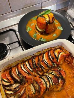 a casserole dish with sliced vegetables in it and another dish on the stove