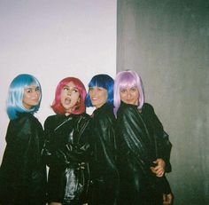 three women with colorful hair standing next to each other in front of a white wall