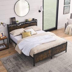 a bed sitting on top of a wooden floor next to a wall mounted mirror above it