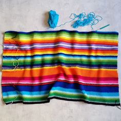 a multicolored knitted blanket with yarn on it