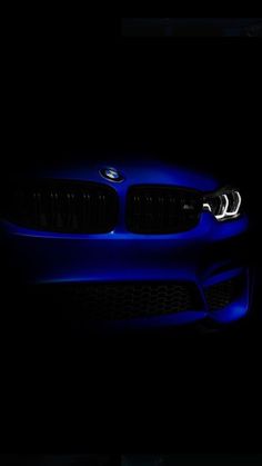 a blue bmw car in the dark with its headlights turned on and it's hood up